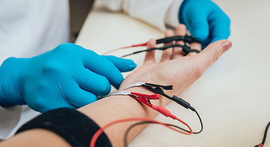 Gros plan sur l'avant-bras d'un patient qui passe un électromyogramme